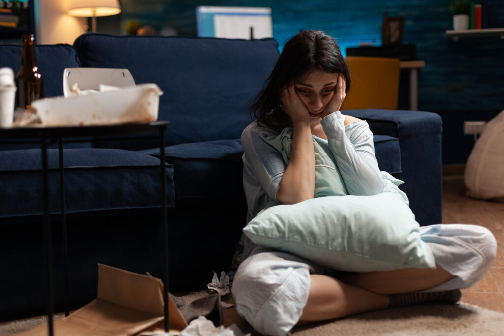 Lonely, traumatised, frustrated, ill woman holding head in hands, feeling vulnerable