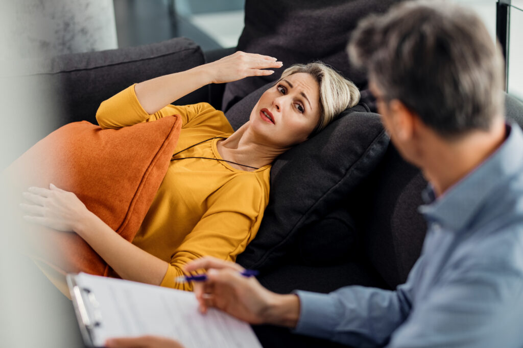 Distraught woman lying down on psychiatrist's couch and talking