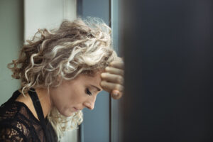 Close-up of upset businesswoman leaning on window in office